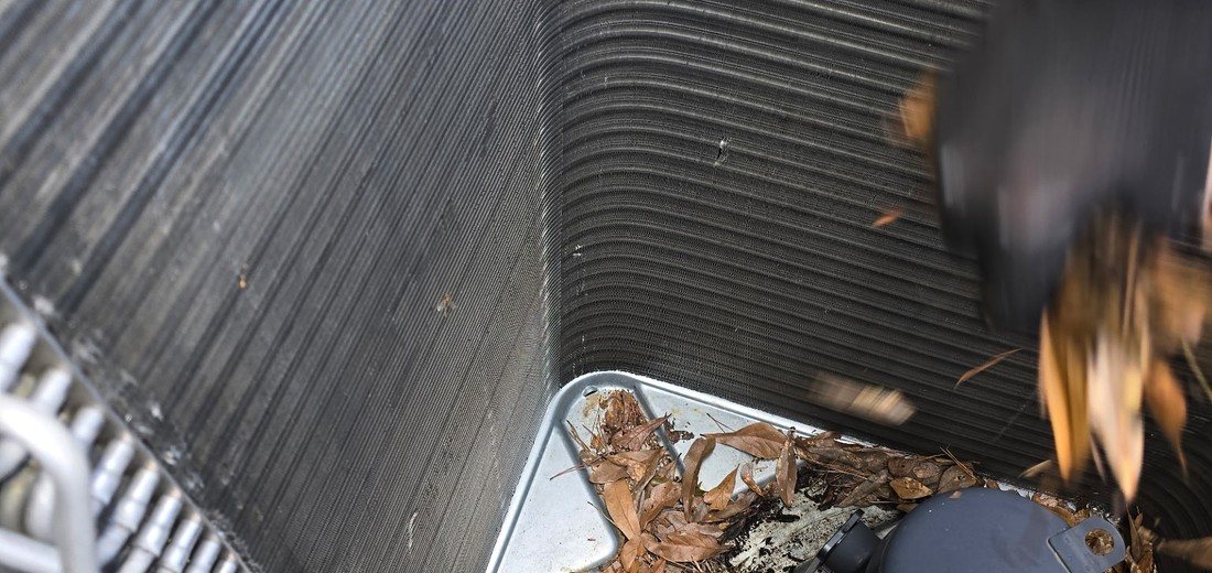 Leaves and debris collected inside an outdoor air conditioning condenser before maintenance