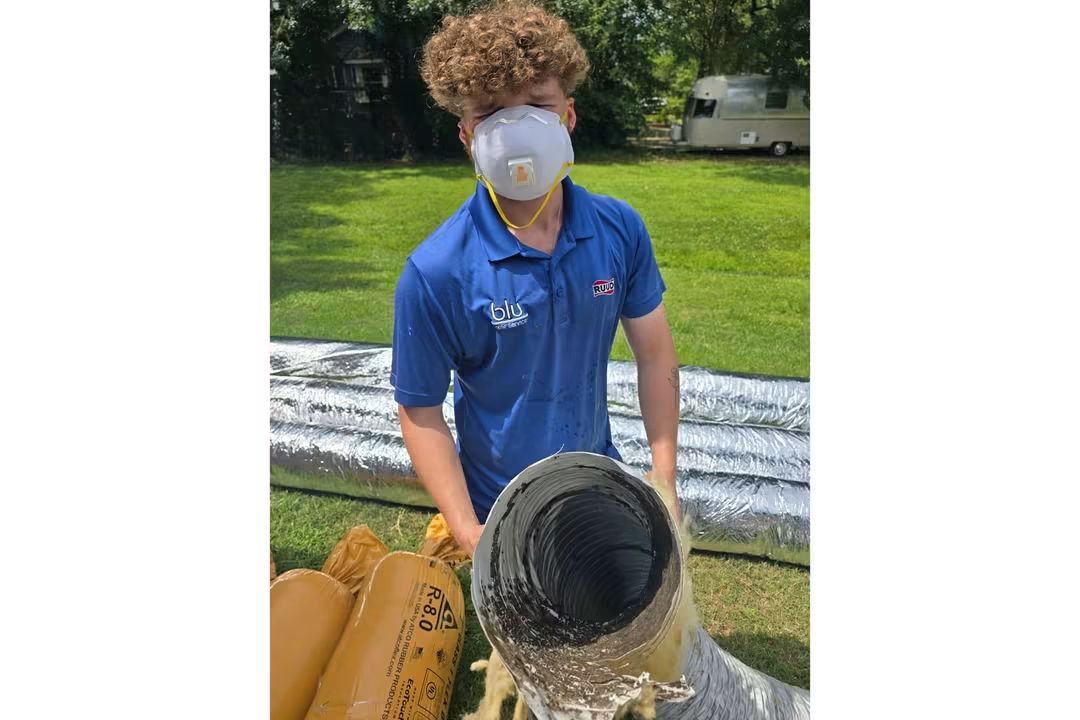 BLU Home Services team member working with ductwork while wearing a protective mask