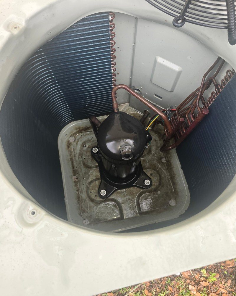 Open residential air conditioner showing condenser coils and compressor during BLU HVAC service